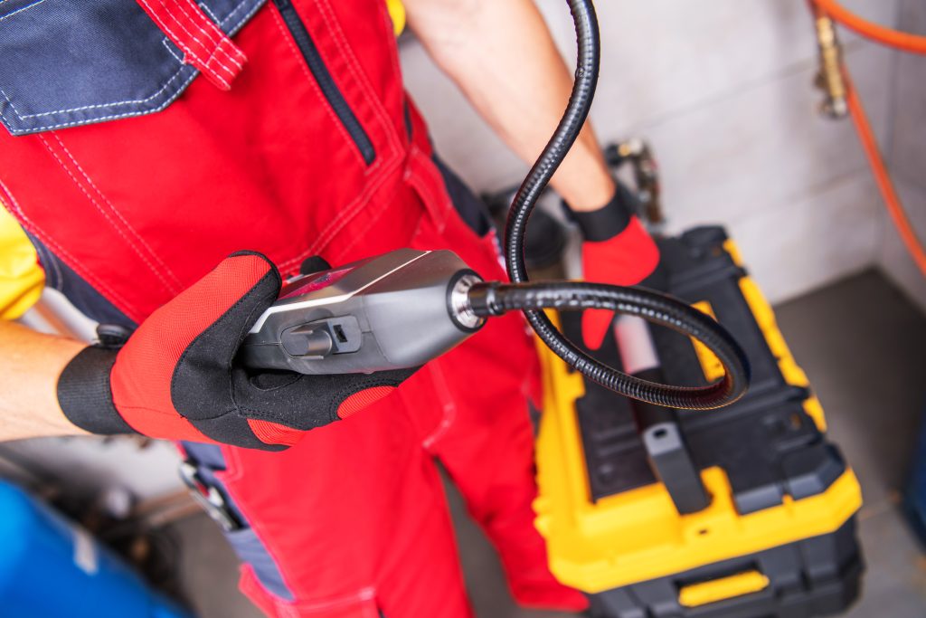 Plumber using advanced leak detection equipment