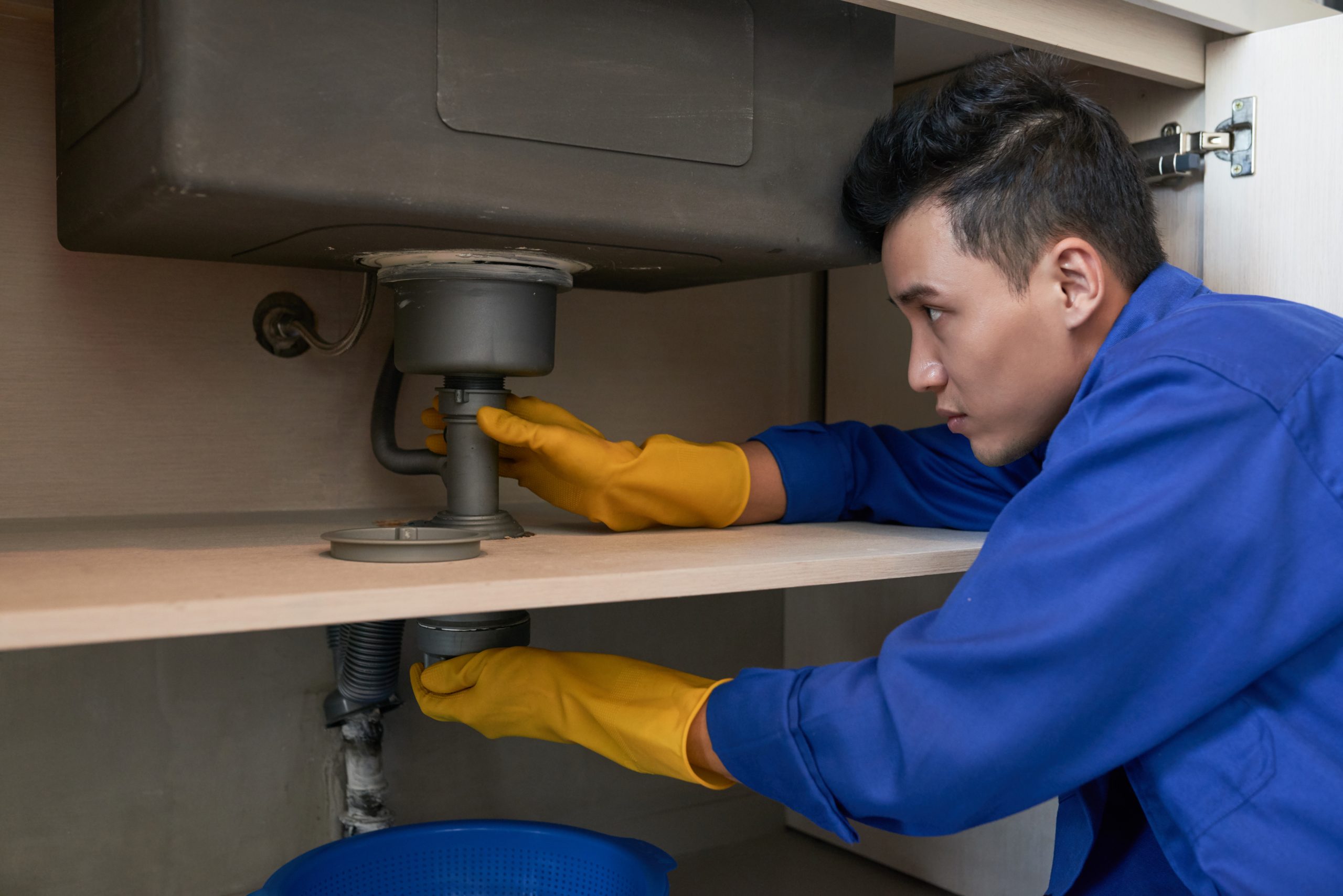 Licensed plumber clearing a clogged drain in an office building