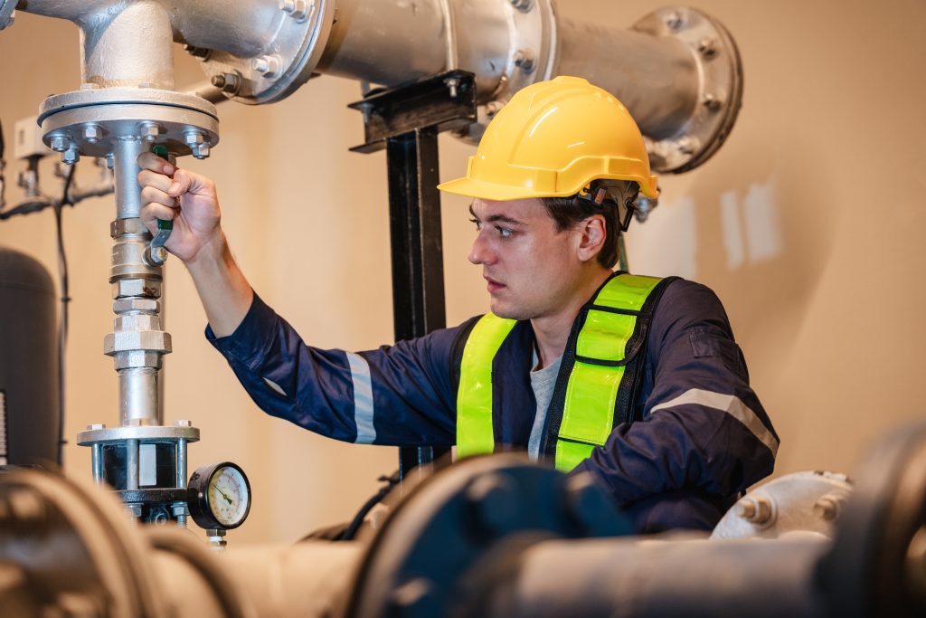 A professional plumber is examining the plumbing and water valves