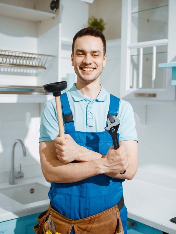 a smiling plumber holding plumbing tools